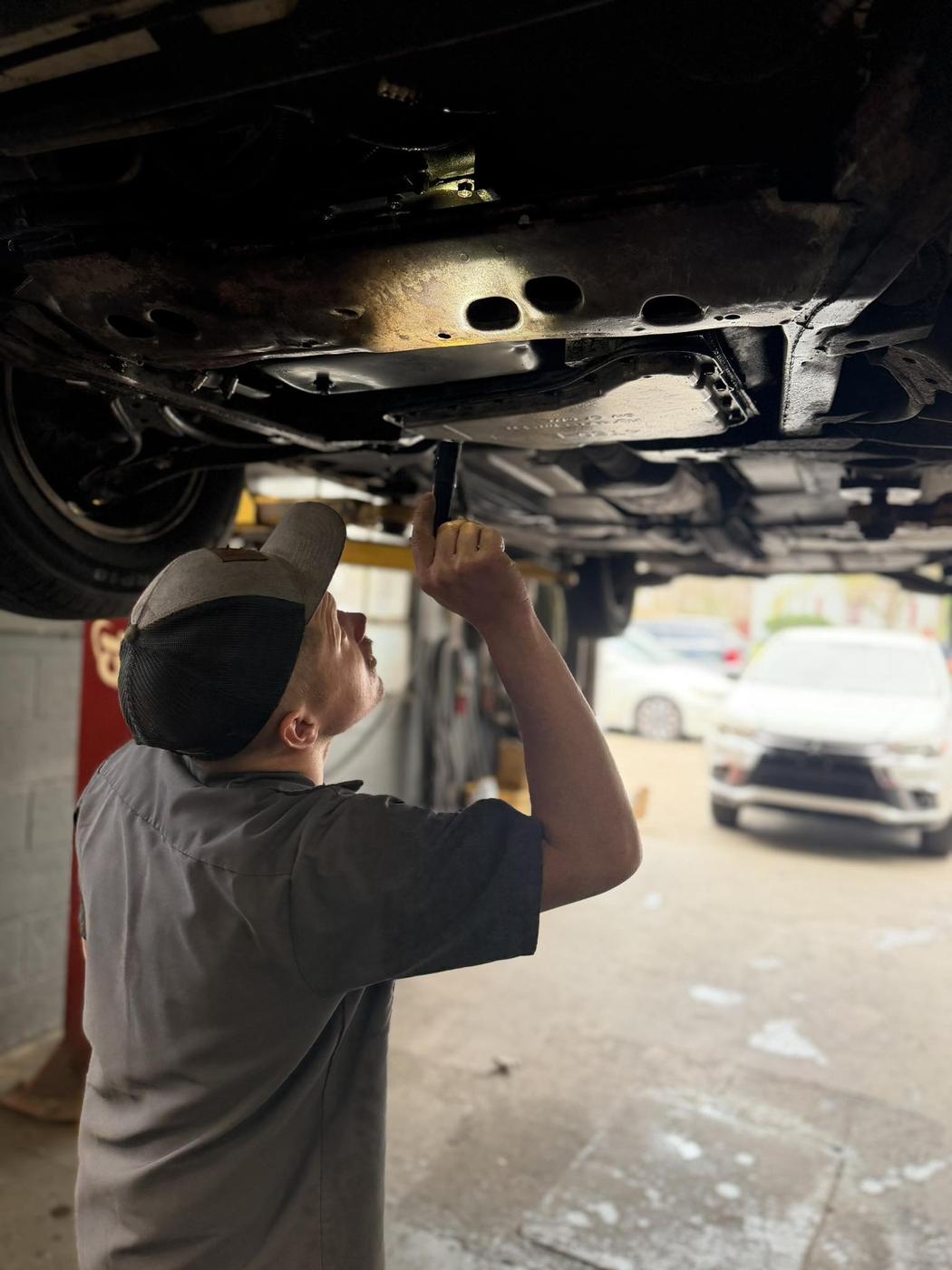 A technician working underneath a car raised on the lift